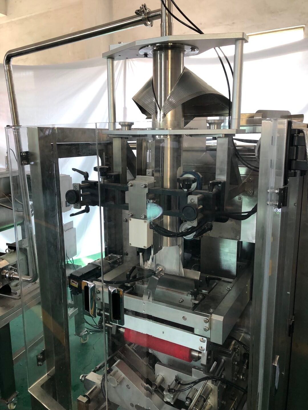 Industrial flour packaging labeling machine filling bags in a factory setting.